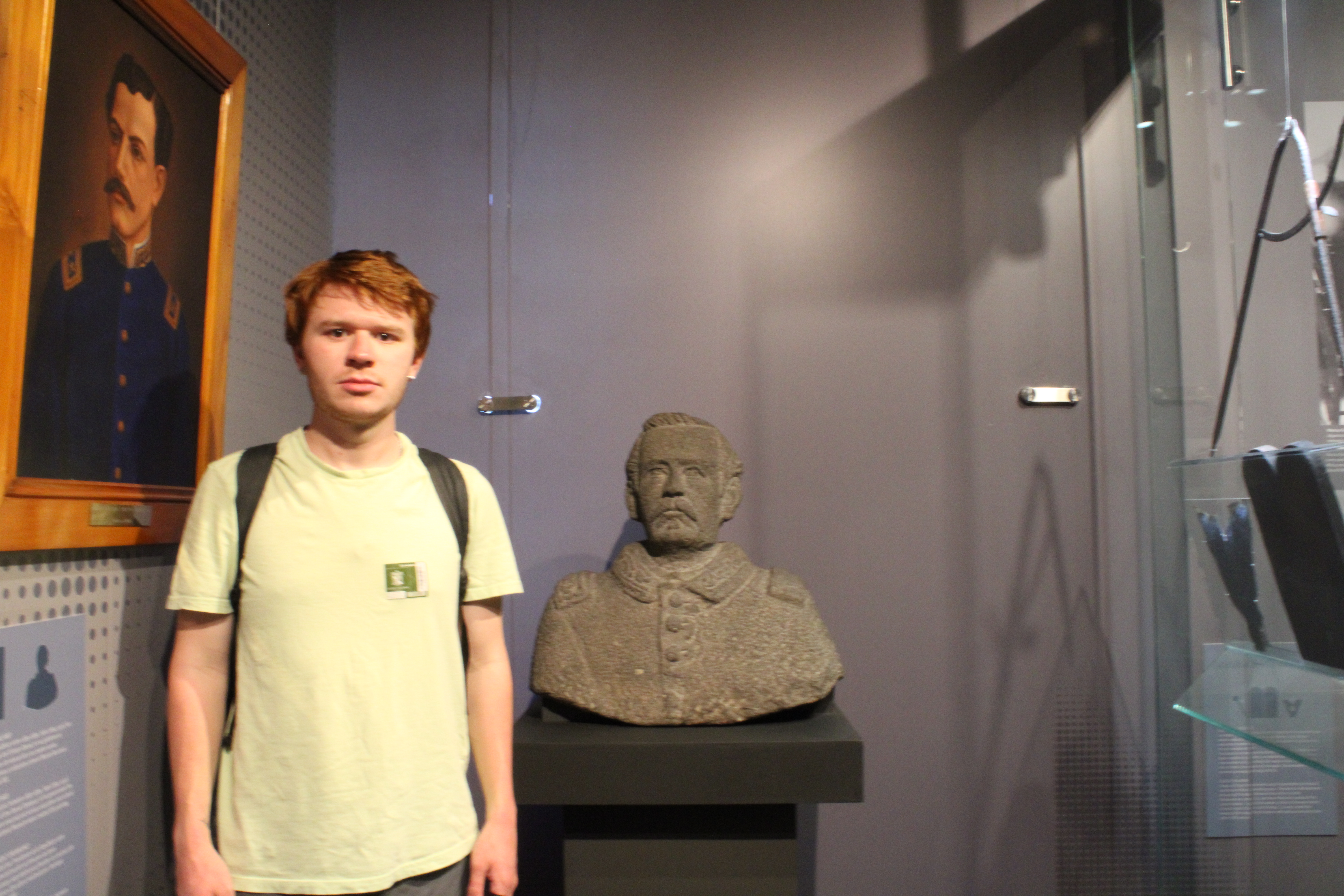 Student in a green shirt next to a bust
